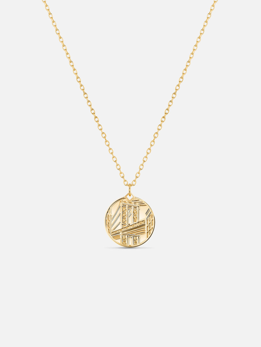 Gold necklace with a round pendant on a white background